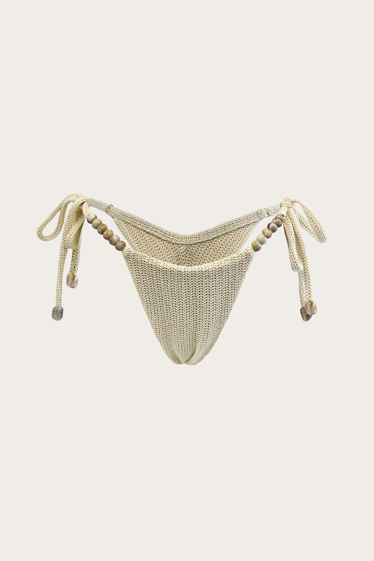 Cream knit thong bikini bottom with beaded side ties against a neutral background